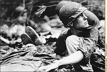 Vietnam War - Combat Chronicles, Photographs of the Vietnam War Part 1 - Waiting for help, A medic from the 1st Battalion, 16th Infantry, 1st Infantry Division, searches the sky for a Medevac helicopter to airlift a wounded buddy following an air assault, June 1967.